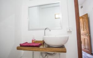 西哈努克欧姆度假屋的木制架子上设有白色碗水槽的浴室