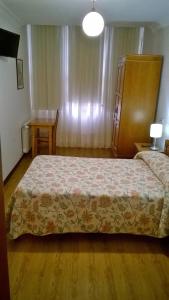 费罗尔Hostal El Cairo的卧室配有1张床、1张桌子和1把椅子