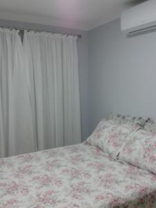 邦比尼亚斯Ótimo Apto. em Bombas的一间卧室配有一张带鲜花毯子的床和窗户。