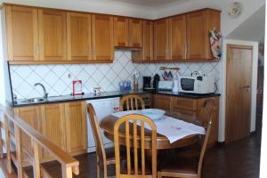 普赖尼亚德拜舒Grande Tranquilidade的一间带桌子的厨房和一间带木制橱柜的厨房
