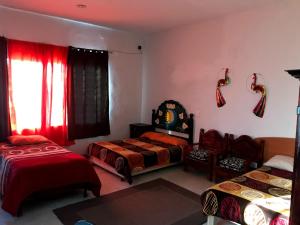 瓜纳华托Las Enredaderas的一间卧室设有两张床,窗户配有红色窗帘