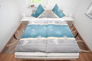 Gangelt苹果园里的度假屋的一张带蓝色和白色床单及枕头的床