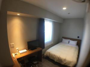磐城小名浜皇冠山酒店的一间卧室配有一张床和一张书桌及电视