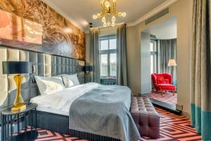 里加Grand Poet Hotel and SPA by Semarah的一间卧室配有一张大床和一张红色椅子
