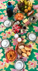 卡拉瓜塔图巴Pousada Tia Cleide的一张桌子,上面放着食物和水果,放在花卉桌布上