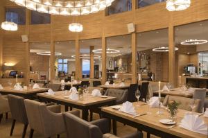 巴特阿罗尔森Hotel Brunnenhaus Schloss Landau的餐厅设有木桌、椅子和吊灯。