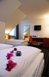 因戈尔施塔特Ara Classic的酒店客房的床上摆放着3张鲜花的床。
