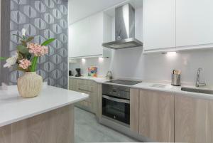 马德里Plaza España & Gran Via 2BD 1BTH的厨房配有白色橱柜和花瓶,位于柜台上