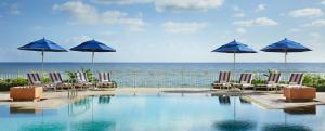 棕榈滩水棕榈海滩度假酒店暨Spa的一个带椅子和遮阳伞的游泳池以及大海