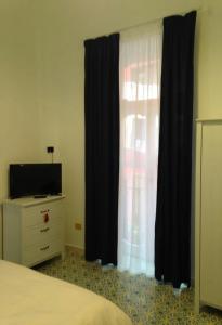 萨莱诺Il sorriso的一间卧室配有床、黑色窗帘和梳妆台