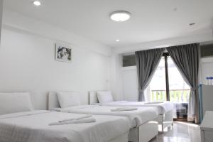 佛丕坦亚查特拉精品公寓式酒店的带窗户的客房内的3张白色床