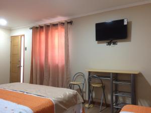 拉塞雷纳Hostal Luna del Mar的客房设有两张床和一台壁挂式平面电视。