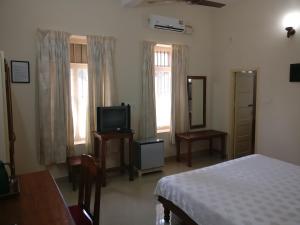 特里凡得琅Safire Residency的一间卧室设有一张床、一台电视和窗户。