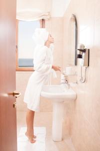 泰尔莫利梅里迪亚诺酒店的站在带水槽的浴室中的女人