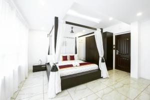 门格洛尔Rahul Residency的卧室配有带白色窗帘的天蓬床