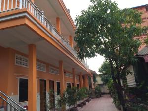 贡布Ta Eng Guesthouse的一座橘色的建筑,在树旁设有楼梯