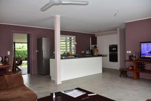 努美阿Bas de villa Noumea的厨房以及带紫色墙壁和柜台的起居室。