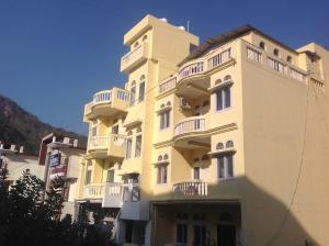 瑞诗凯诗Seventh Heaven Inn Rishikesh的一座高大的黄色建筑,设有白色阳台
