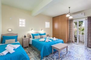斯塔菲罗斯Stafylos Suites & Boutique hotel的一间卧室配有两张带蓝色床单的床和一张桌子