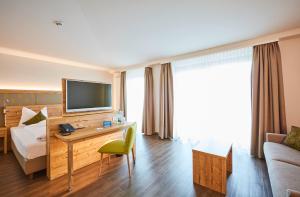 巴特温茨海姆维塔尔特尔姆GmbH酒店的酒店客房配有一张床和一张书桌及一台电视