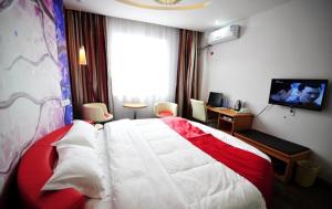 安顺尚客优连锁贵州安顺开发区西航路店的卧室配有红色和白色的床和电视。