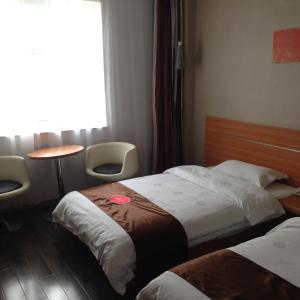 安顺尚客优连锁贵州安顺开发区西航路店的酒店客房设有两张床、一张桌子和一个窗户。