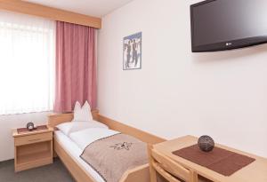 布拉伊埃斯盖斯特霍夫胡伯酒店的卧室配有一张床,墙上配有电视。