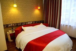 Yanjun尚客优连锁辽宁鞍山海城万达店的一张红色和白色的床,位于酒店客房内