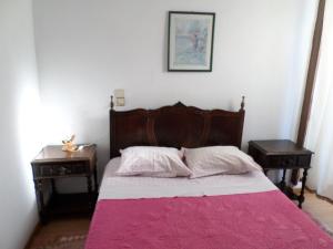 维拉·雷阿尔Rustico & Singelo - Hotelaria e Restauração, Lda的一间卧室配有一张带粉色毯子的床和两张桌子