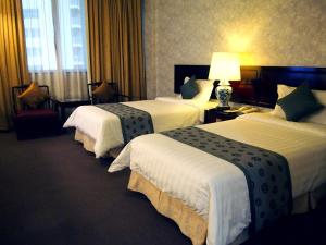 新加坡Hotel Royal的酒店客房,设有三张床和一盏灯