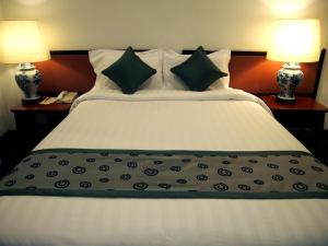 新加坡Hotel Royal的一间卧室配有一张大床和两盏灯