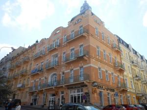 玛丽亚温泉Balconies above colonnade apartments的一座黄色的大建筑,前面有汽车停放