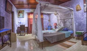 瓦加杜古Le Karite Bleu的紫色客房内的一间卧室配有一张天蓬床