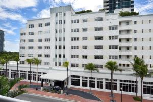 迈阿密海滩迈阿密海滩时代酒店的一座白色的建筑,前面有棕榈树