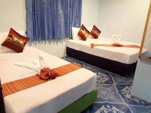 Baan Khai班科隆旅馆的一间设有三张床的房间,上面有弓
