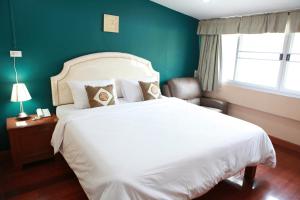曼谷PR之地酒店的卧室配有白色的床和绿色的墙壁