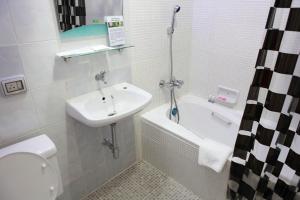 曼谷PR之地酒店的浴室配有盥洗盆、卫生间和浴缸。