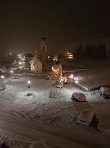 科尔福索Ciasa Gabriel的一座雪覆盖的小镇,晚上有教堂