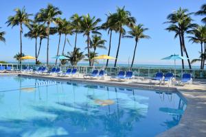迈阿密海滩迈阿密海滩海岸套房公寓式酒店的一个带椅子和棕榈树的游泳池以及大海