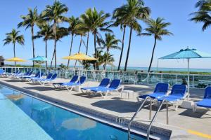 迈阿密海滩迈阿密海滩海岸套房公寓式酒店的游泳池旁的一排椅子和遮阳伞