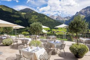 米特尔贝格Haller's Geniesserhotel的餐厅配有桌椅,位于山脉的背景中