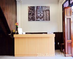 素可泰日德拉度假酒店的一张桌子,墙上挂着雕像的照片