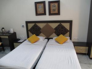 新德里东区度假酒店的一间卧室配有两张带黄色枕头的床