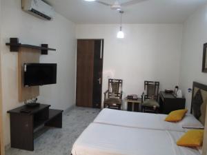 新德里东区度假酒店的一间卧室配有一张床和一台平面电视