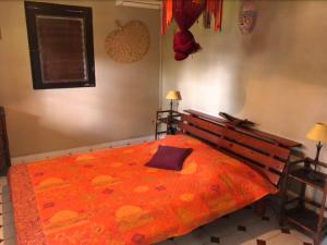 Ducos堡甘维里尔简易别的一间卧室配有一张带橙色毯子的大床