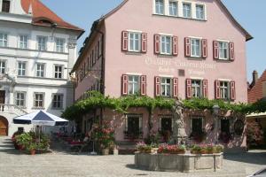 伊普霍芬Gasthof & Hotel Goldene Krone的一座粉红色的建筑,前面有雕像