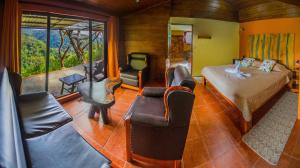 蒙泰韦尔德哥斯达黎加哥斯达黎加彩虹谷山林小屋的一间卧室配有一张床、一张沙发和椅子