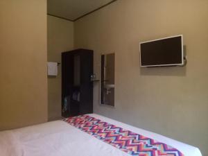 金巴兰巴厘岛乌鲁民宿的一间卧室配有一张床和一台平面电视