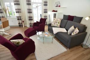 宾茨Haus Metropol - Fewo 7 mit Balkon und Meerblick的客厅配有灰色的沙发和红色的椅子