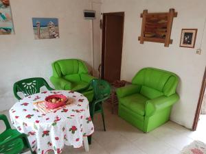 阿加斯杜尔斯Los Lachos的一间用餐室,配有绿色椅子和一张带一碗水果的桌子